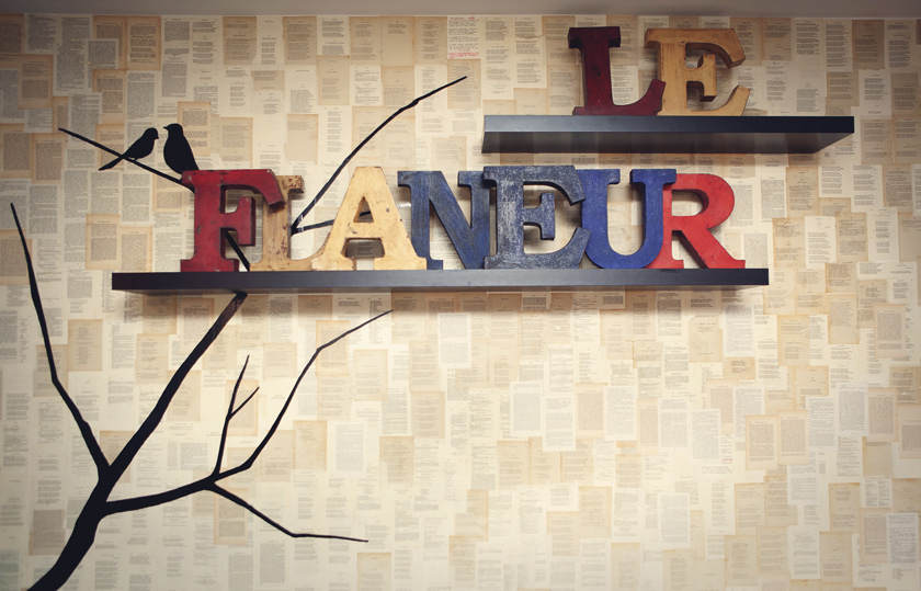pared con poemas de Baudelaire estanterías con letras de madera de colores Le Flaneur árbol y cuervos 
