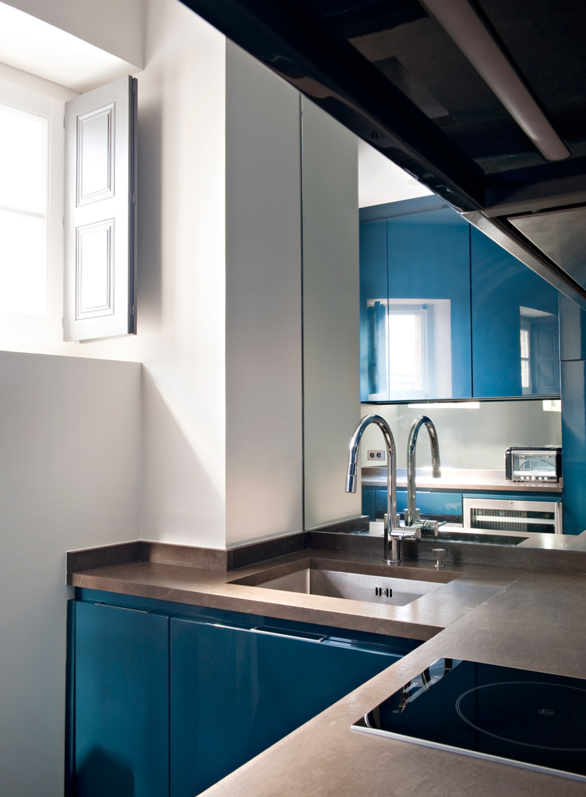 cocina con muebles azules brillantes paredes blancas y ventana pica grifo 
