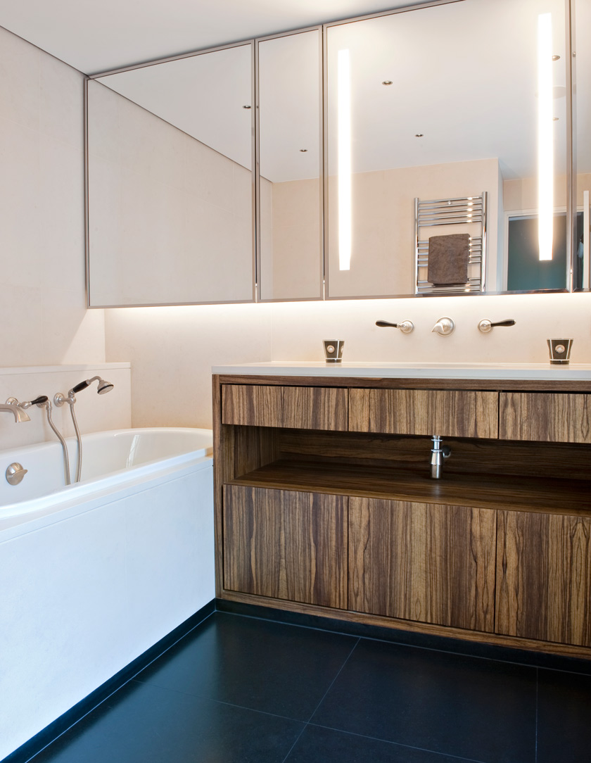 baño principal con bañera alicatado en beige suelo con baldosas negras mate mueble de baño madera oscura espejo bañera