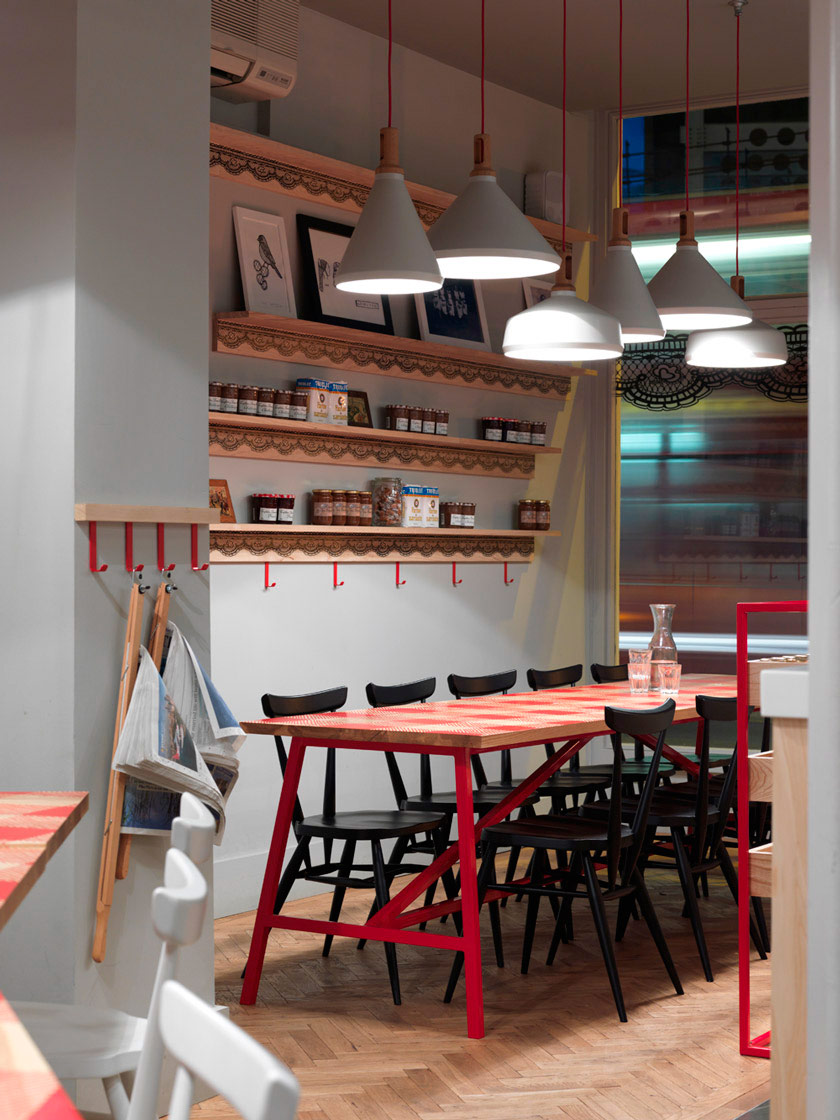 paredes blancas sillas negras y rojas mesa con mantel tipico de la bretaña francesa periodicos ventanal