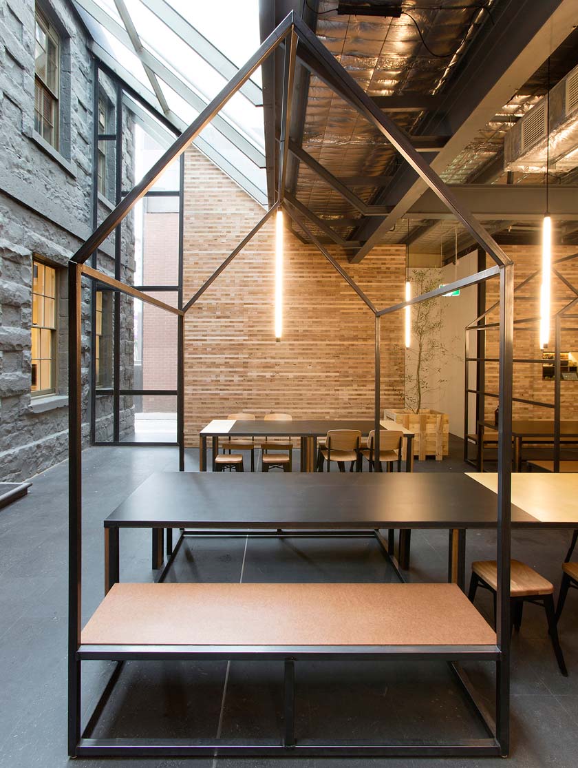 exterior con estructuras metalicas y mesas con sillas de madera, iluminación suave.