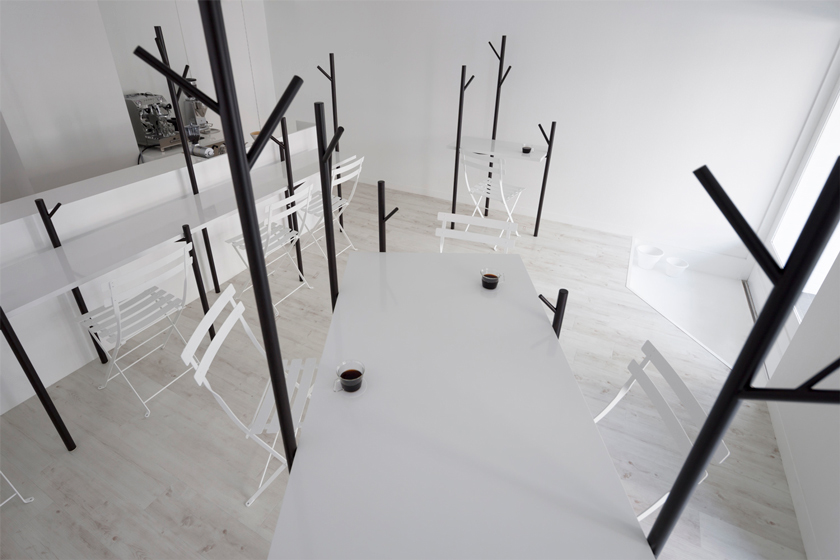 perspectiva cafetería barra blanca con cafetera industrial espacio en blanco con ramas de árbol