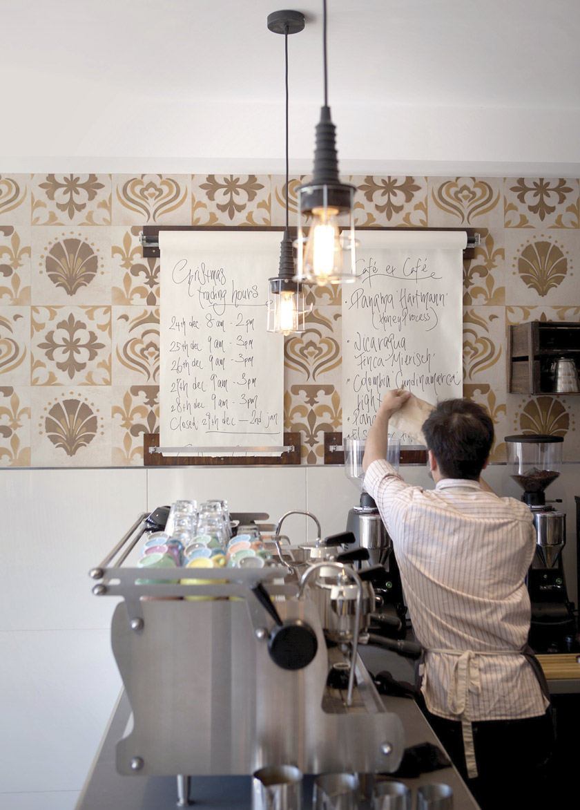 menú horario en rollos de papel colgados en pared de baldosas customizadas marrón cafetera industrial camarero