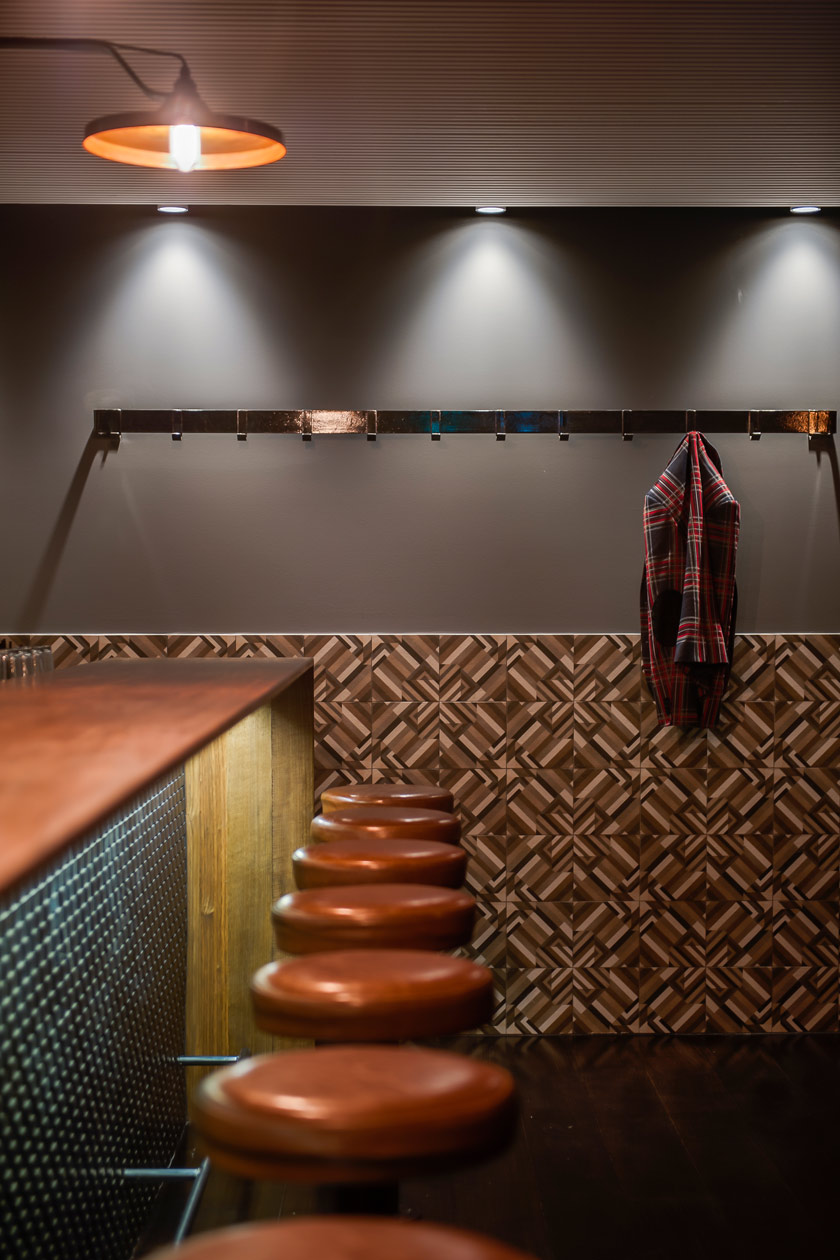 asientos de cuero en taburetes altos de bar pared alicatada y colgador con camisa a cuadros