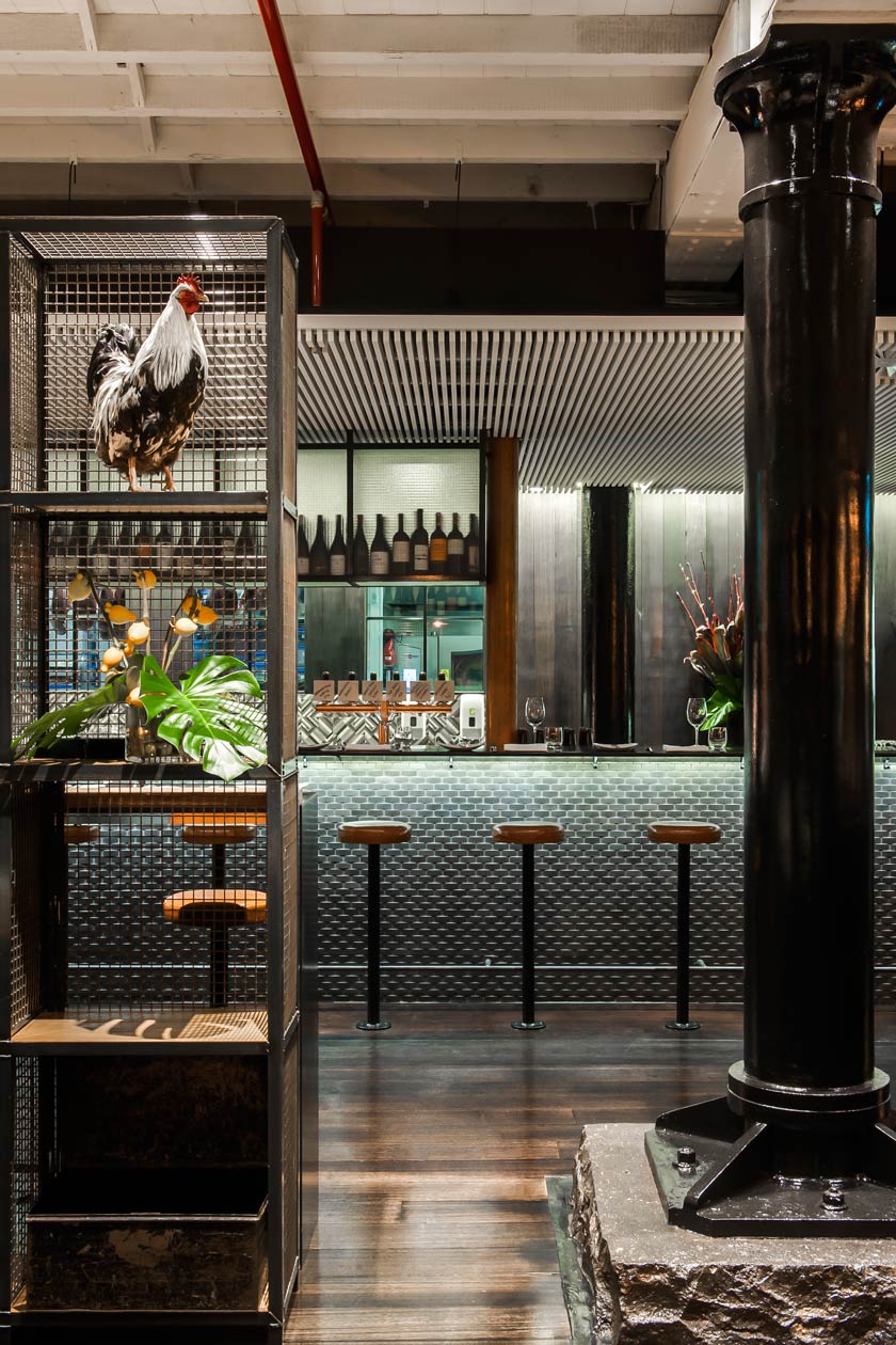 estanterias de reja con gallina y elementos decorativos zona de bar y cocina de restaurante y columna sobre base de cemento